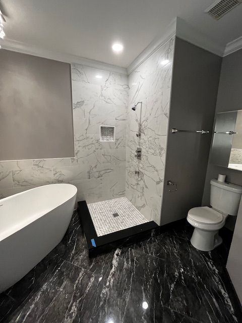 Luxurious bathroom with marble shower, freestanding tub, and dark tiled floor.