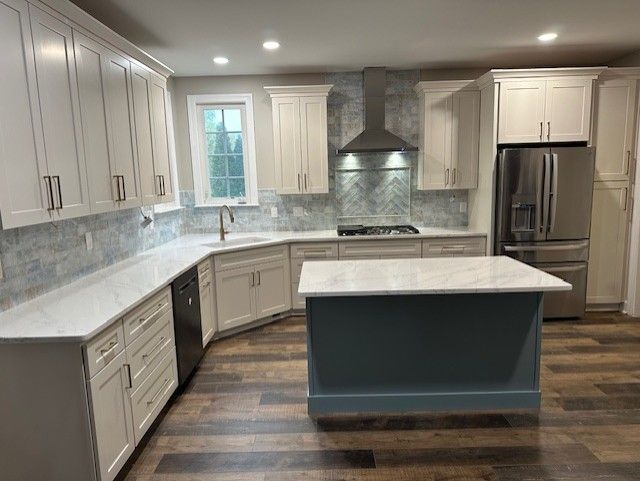 Modern kitchen with white cabinets, blue island, stainless steel appliances, and patterned backsplash.