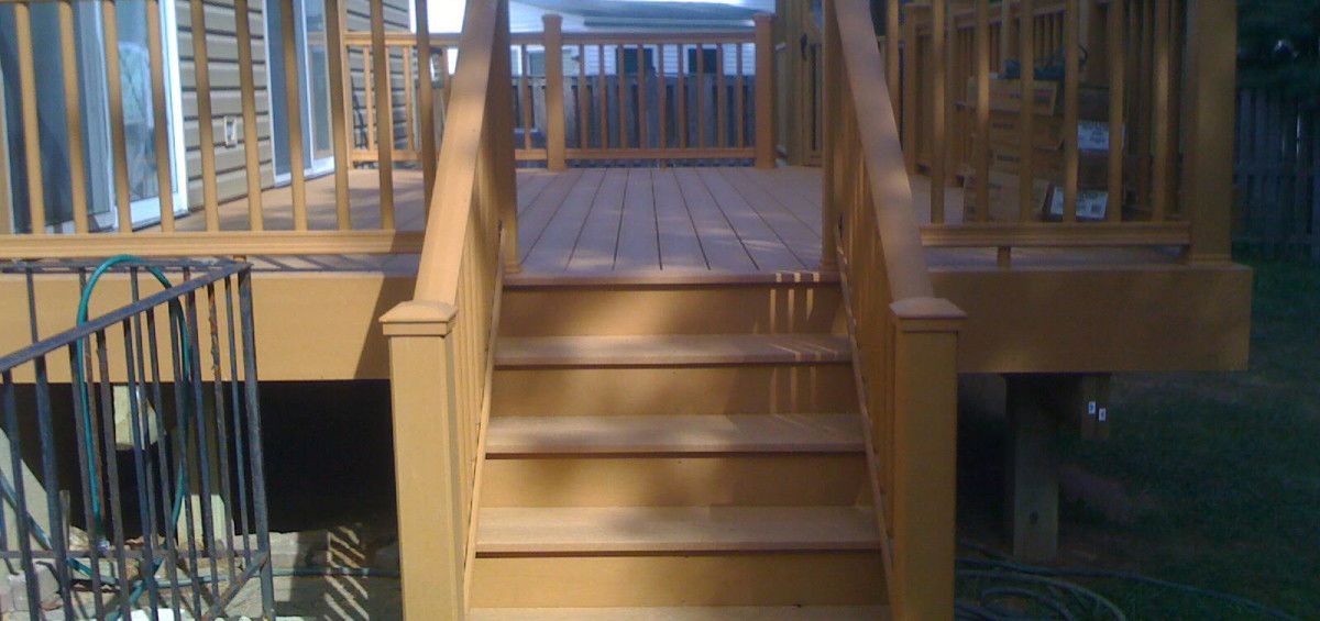Wooden deck with stairs, railings, and warm-toned paint in an outdoor setting.