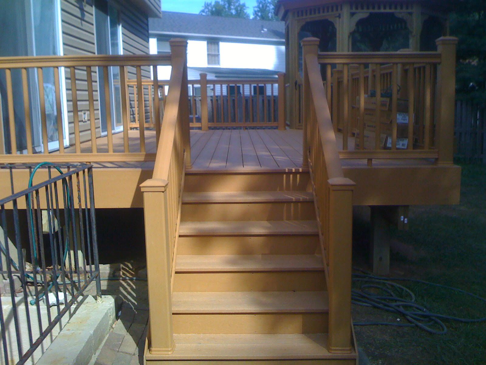 Wooden deck with steps leading up, railing, brown tones, outdoor setting.