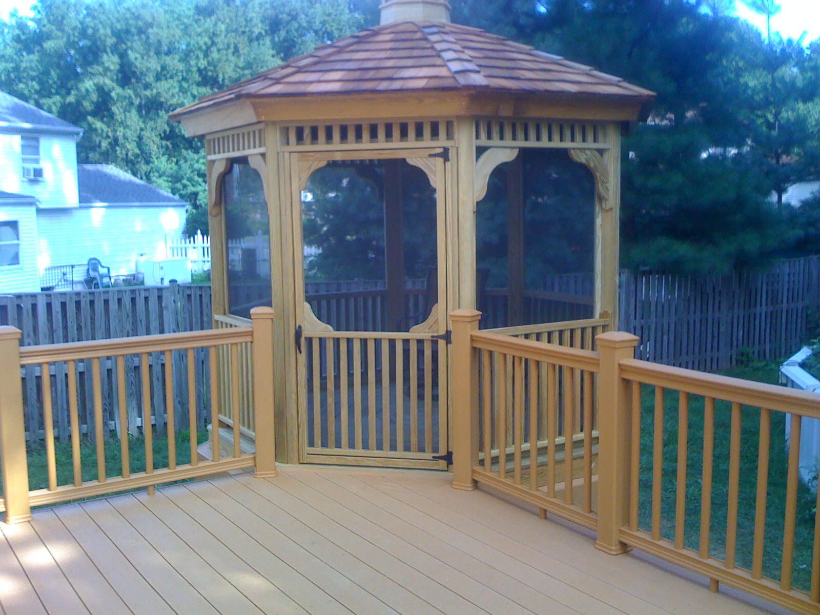 Wooden gazebo on a deck; light brown with screen panels; backyard setting.