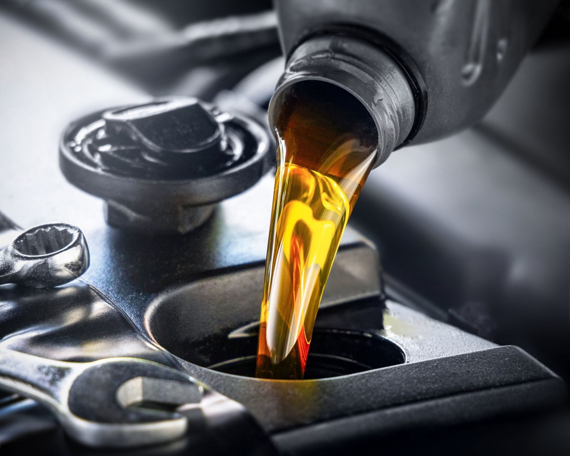 Motor oil pouring from a bottle into a car engine fill port
