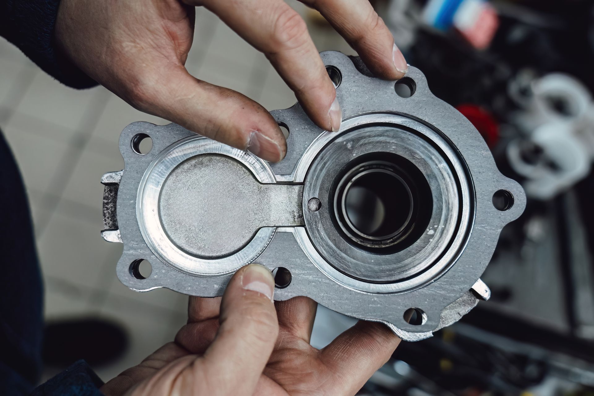 Hands holding an open metal mechanical part with a circular bearing, close-up.