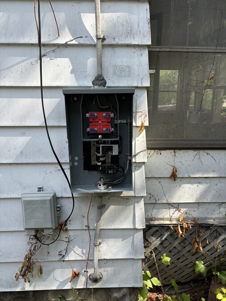 An electrical box is attached to the side of a house.