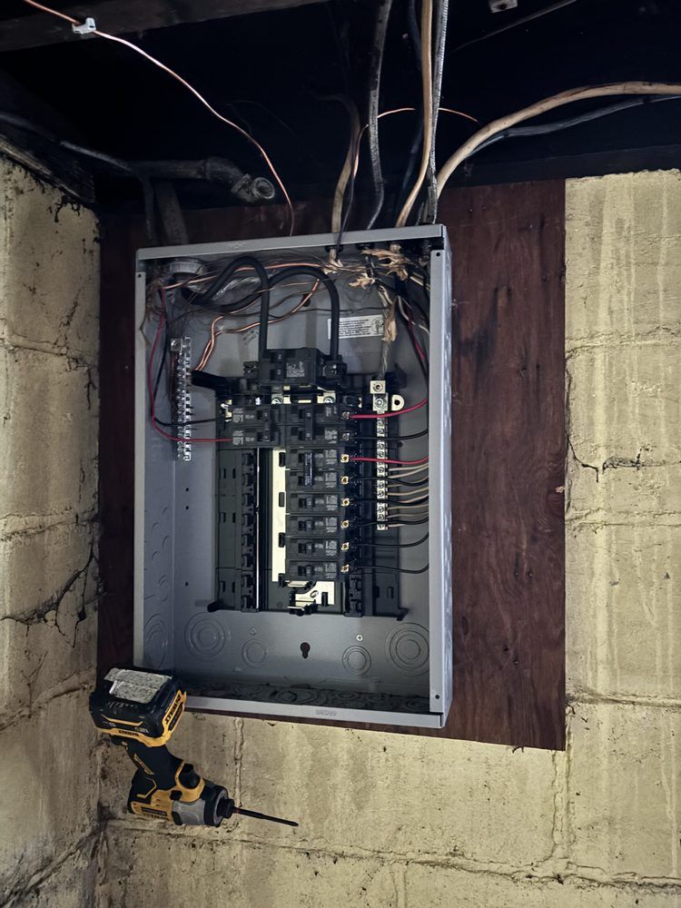 A drill is sitting next to a electrical box on a brick wall.