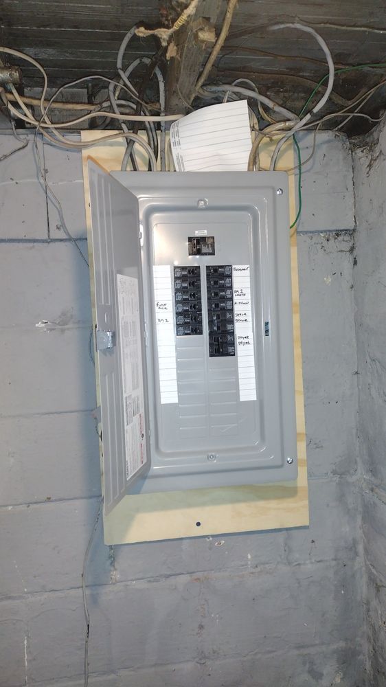 A gray electrical box is hanging on a brick wall.