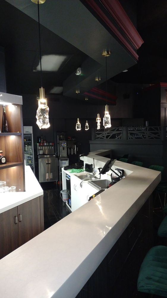 A bar in a restaurant with a lot of lights hanging from the ceiling