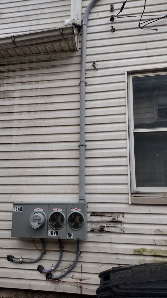 An electrical box is attached to the side of a house.