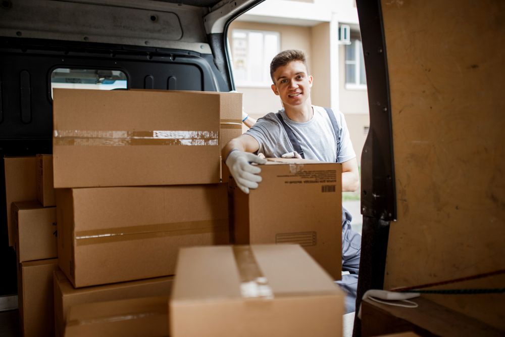 A Man is Loading Boxes Into the Back of a Van — Davis Removals & Storage in Townsville, QLD