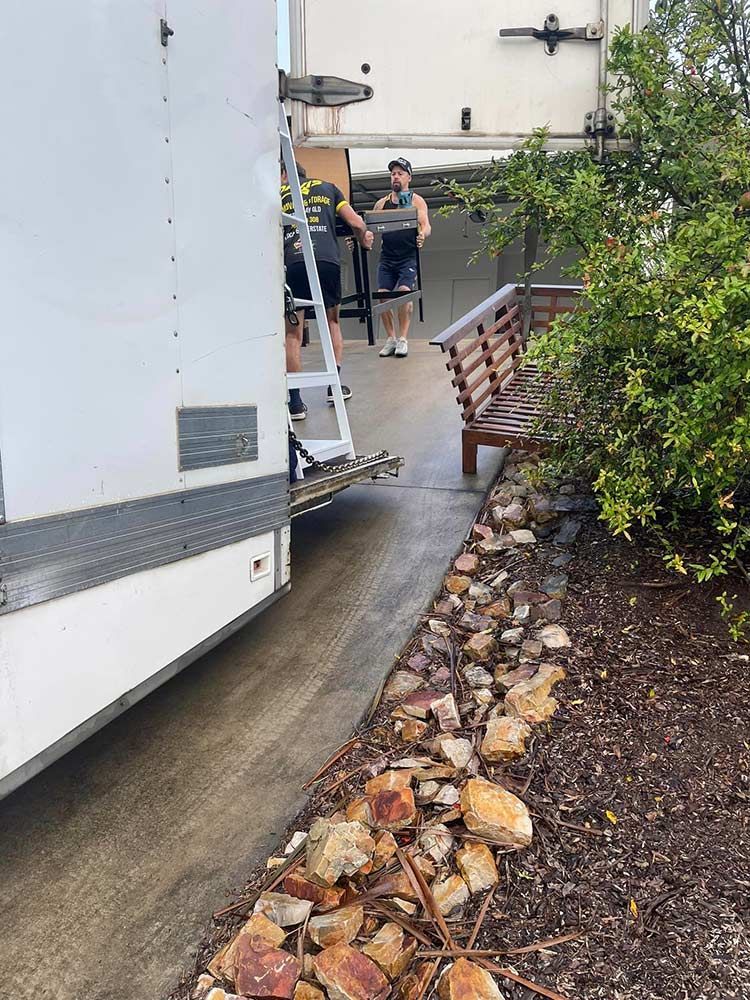 A White Truck is Parked in a Driveway Next to a Bench — Davis Removals & Storage in Dundowran, QLD