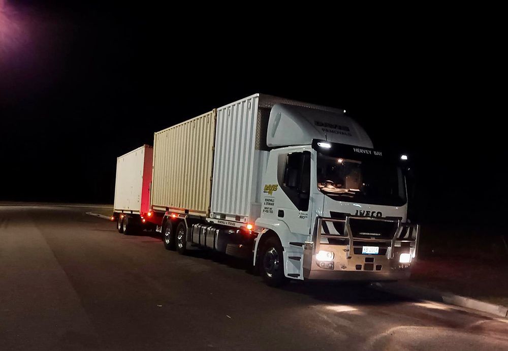 A White Truck is Driving Down a Road at Night — Davis Removals & Storage in Maryborough, QLD
