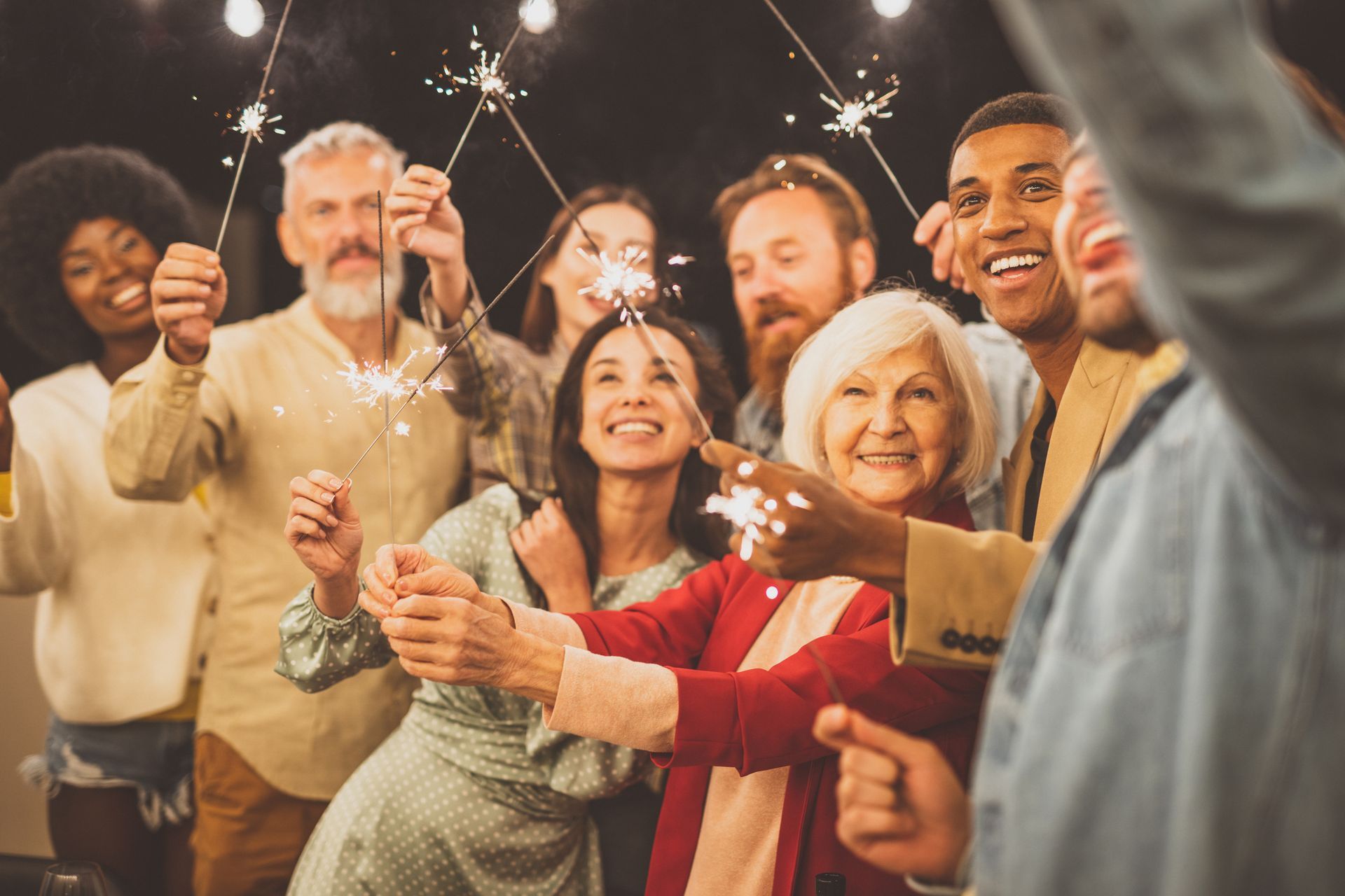 A group of people are holding sparklers at a party.