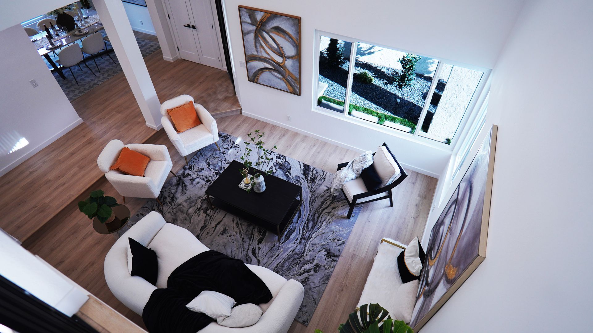 High-angle view of a modern living room featuring white furniture, a black coffee table, and a grey patterned area rug.