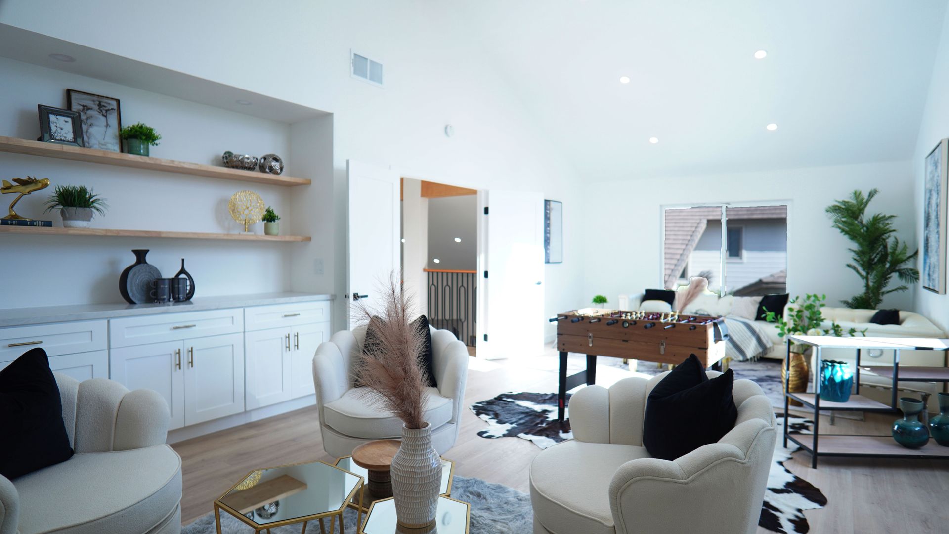 A modern dining area with a long wooden table, six black chairs, and tall windows looking out onto a snowy, wooded scene.