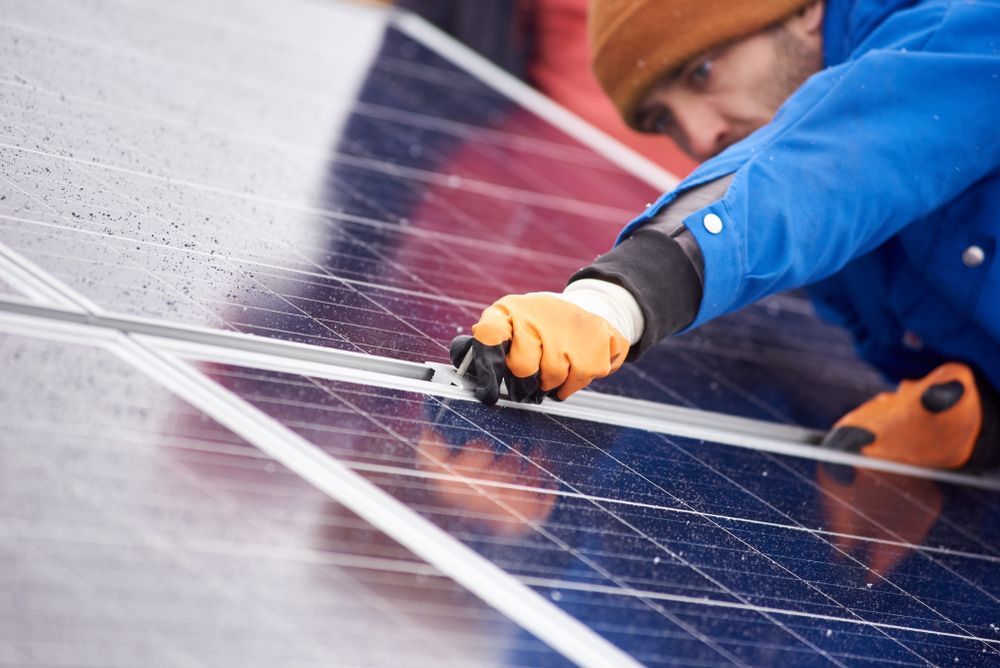 Person in Orange Gloves and Blue Jacket Installing Solar Panels — Gold City Solar & Electrical in Maryborough, QLD