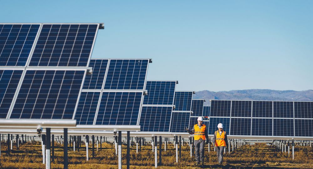 Two Workers in Safety Vests Walking by Solar Panels — Gold City Solar & Electrical in Sunshine Coast, QLD