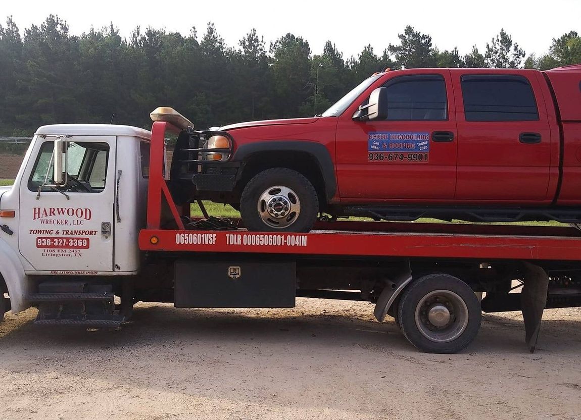 A Tow Truck With A Red Truck on The Back Of It