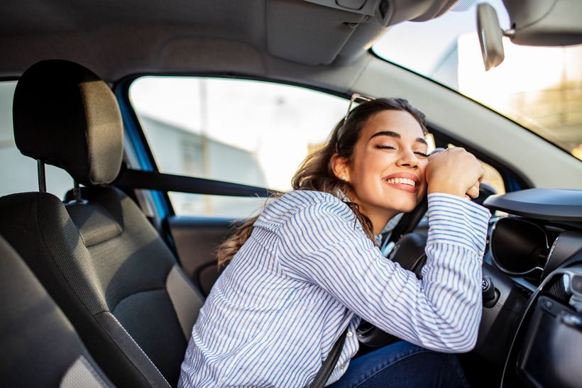 A woman is sitting in the driver 's seat of a car talking on a cell phone.