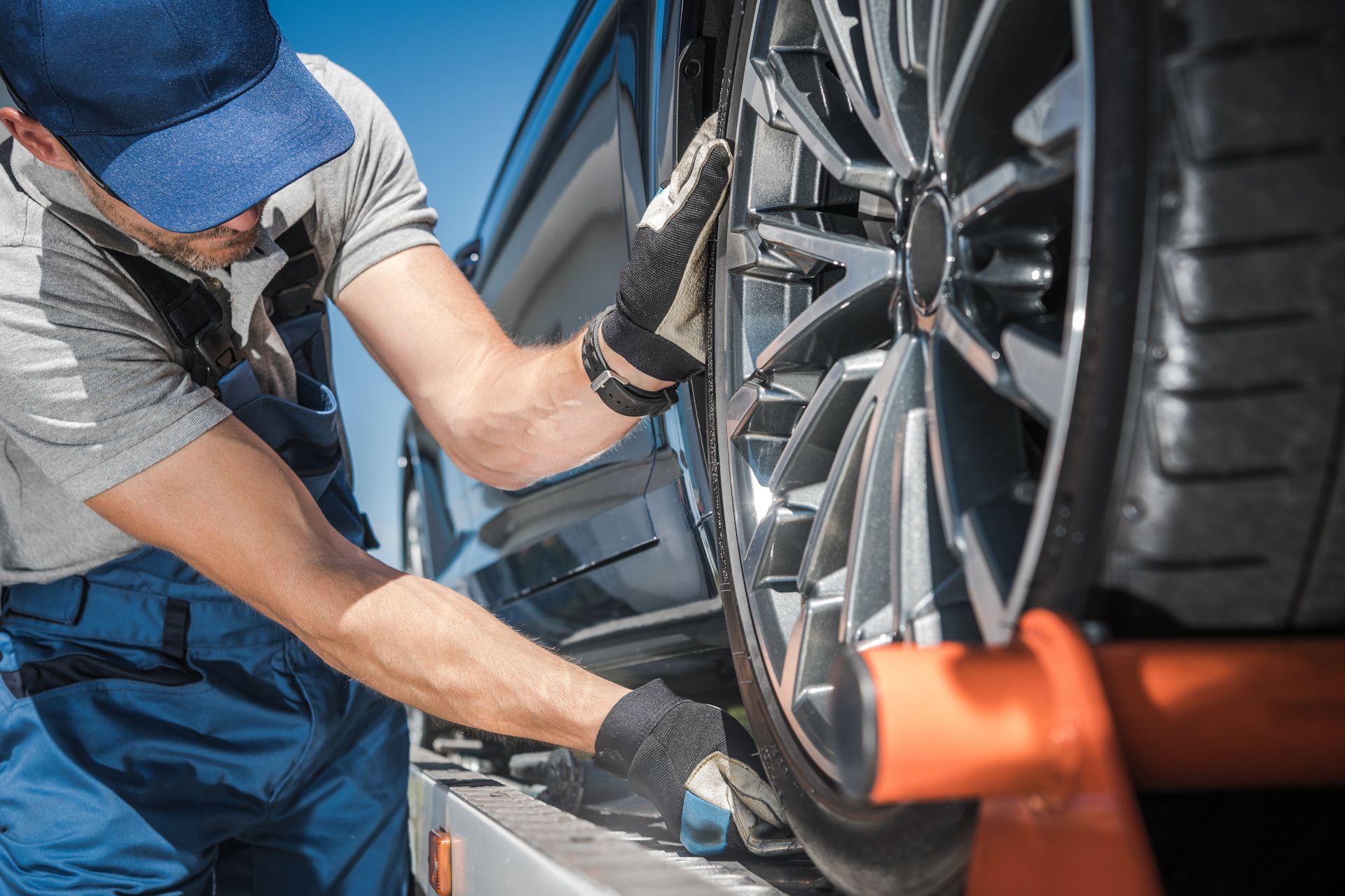 A man is working on a car wheel on a lift.