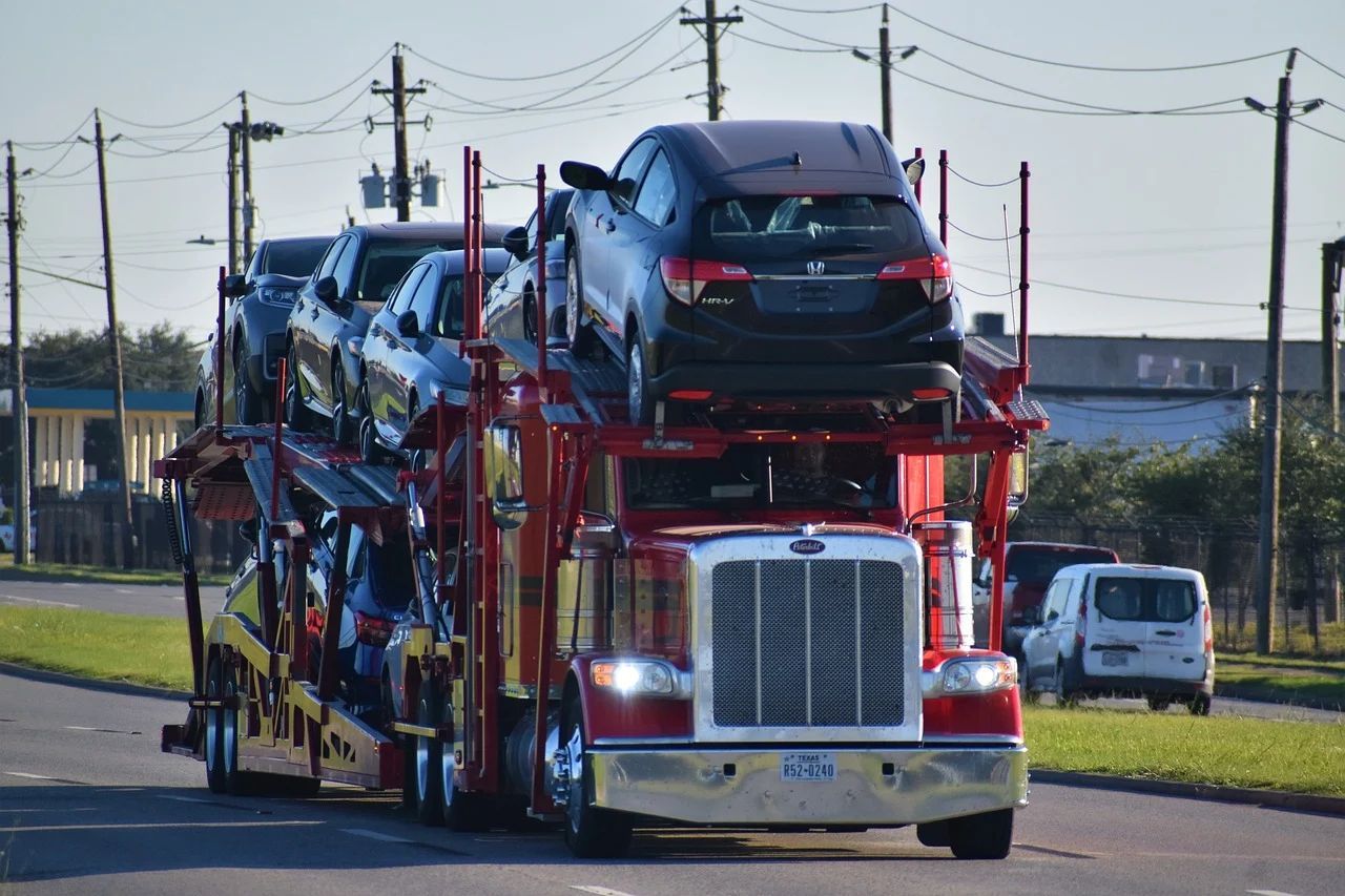 A car carrier truck is driving down the road carrying a row of cars.