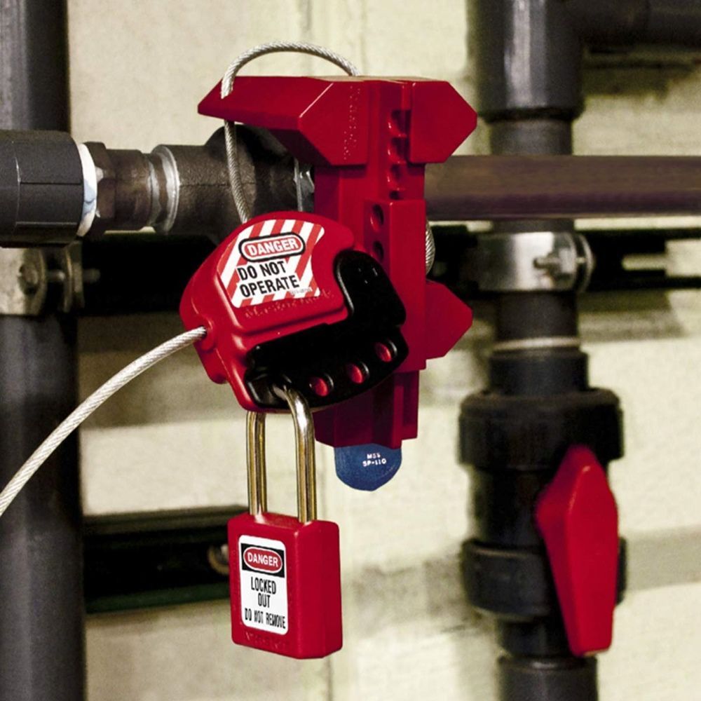 Red lockout device and padlock securing a valve on industrial pipes. 