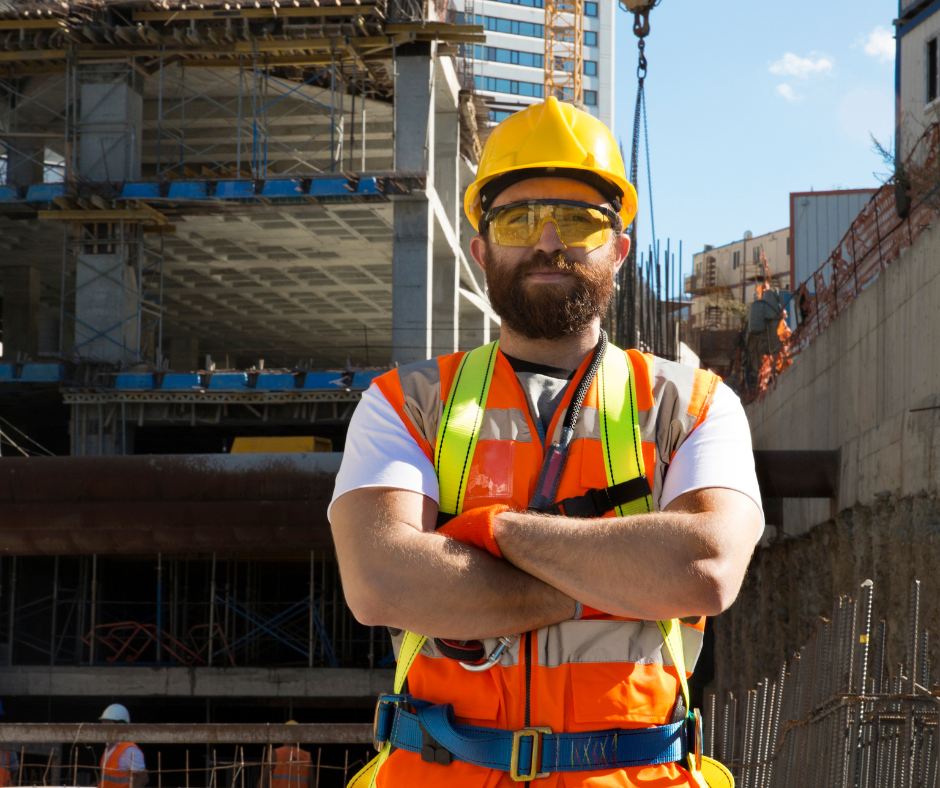 Safety gear: high-visibility vest, safety glasses, ear muffs, work gloves, and yellow hard hat arranged on a white surface.