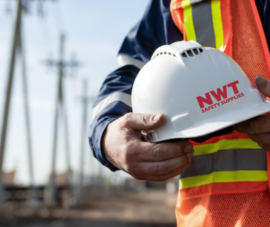 Person in work attire holding a white hard hat with red 