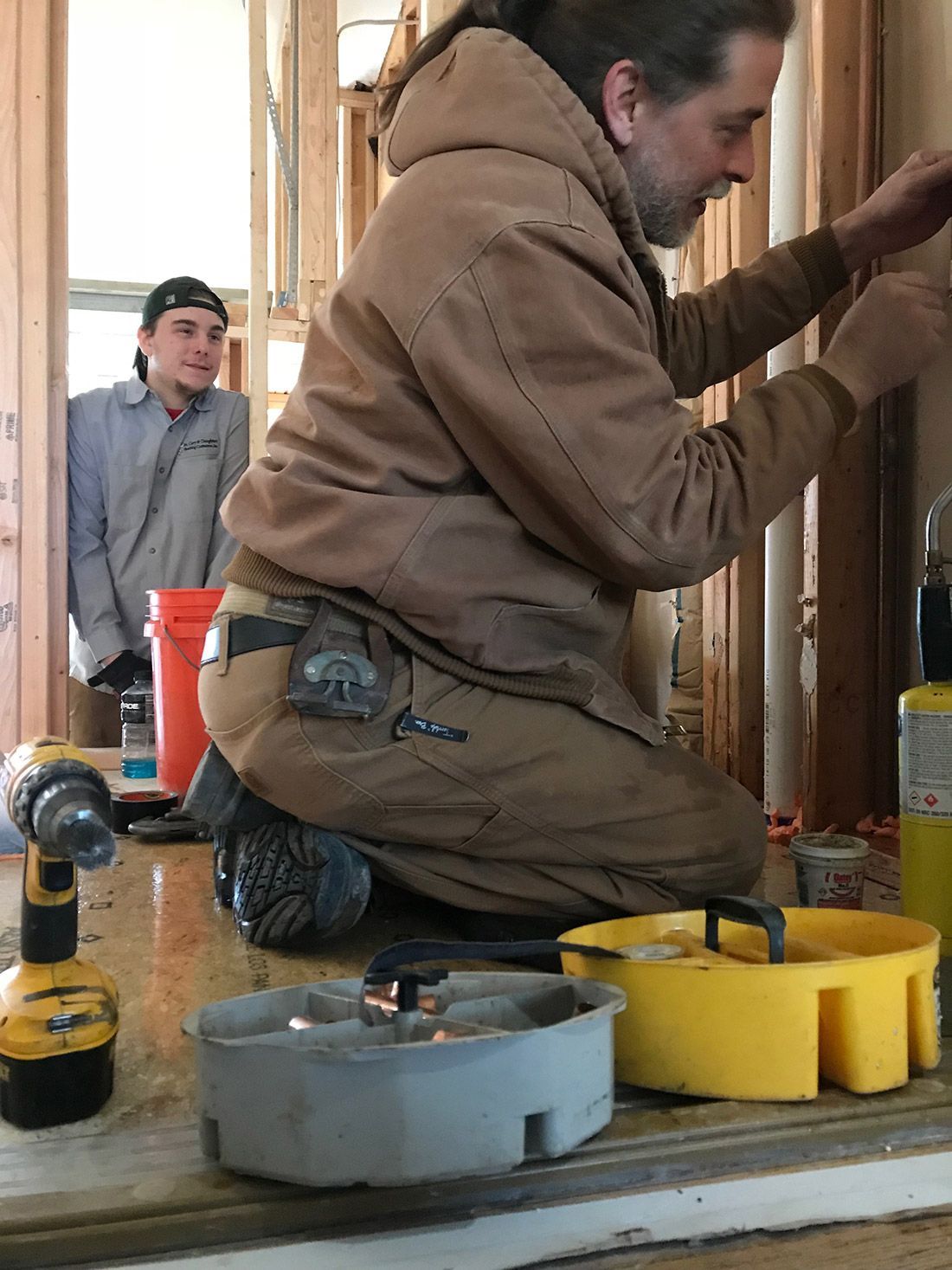 A man is kneeling down while working on a wall.