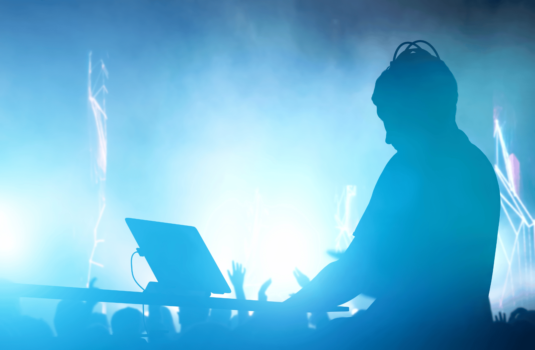 A silhouette of a dj playing music in front of a crowd.