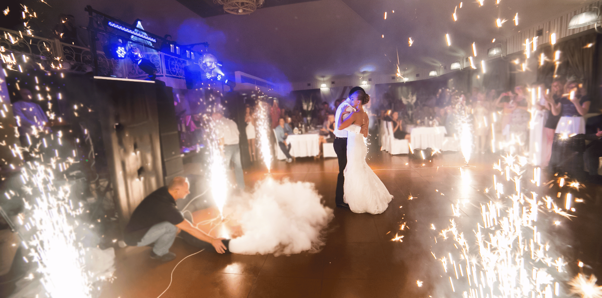 A bride and groom are dancing in front of fireworks at their wedding reception.