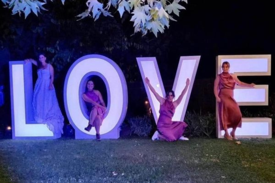 A group of women standing in front of a large love sign