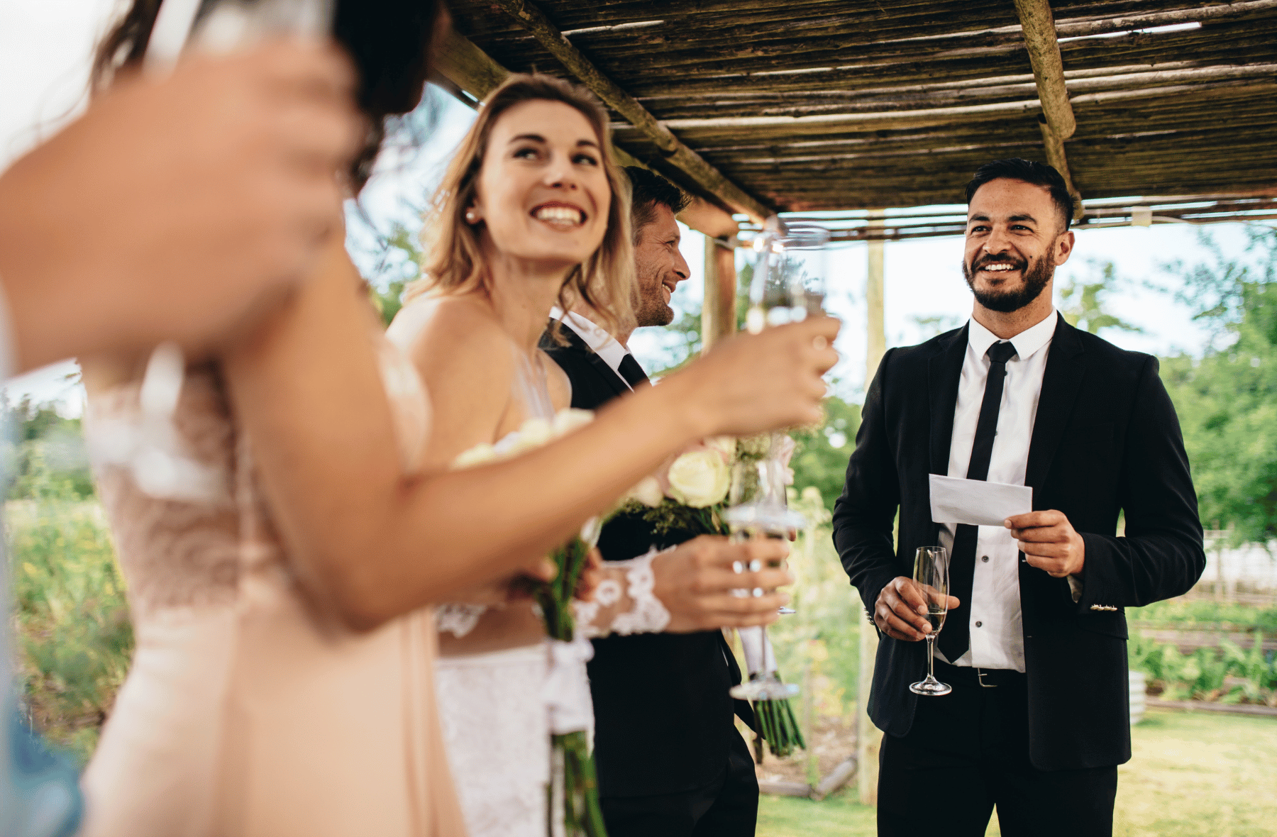 A man in a suit is giving a speech at a wedding reception.