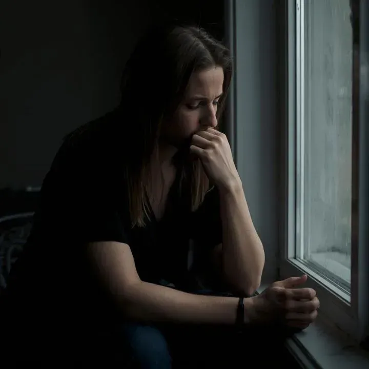 Person sitting quietly with a concerned expression, reflecting on relationship doubts and seeking cl