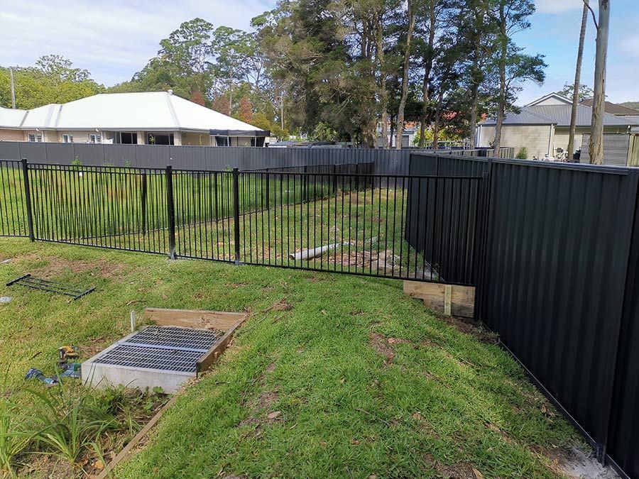 A Black Fence is Surrounding a Grassy Field Next to a House — WeFence in Lisarow, NSW