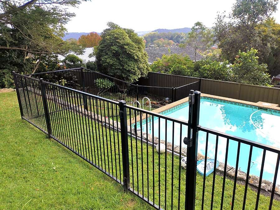 A Black Metal Fence Surrounds a Swimming Pool in a Backyard — WeFence in Lisarow, NSW