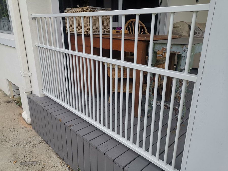 A white railing on a porch with a table and chairs behind it — WeFence in Lisarow, NSW