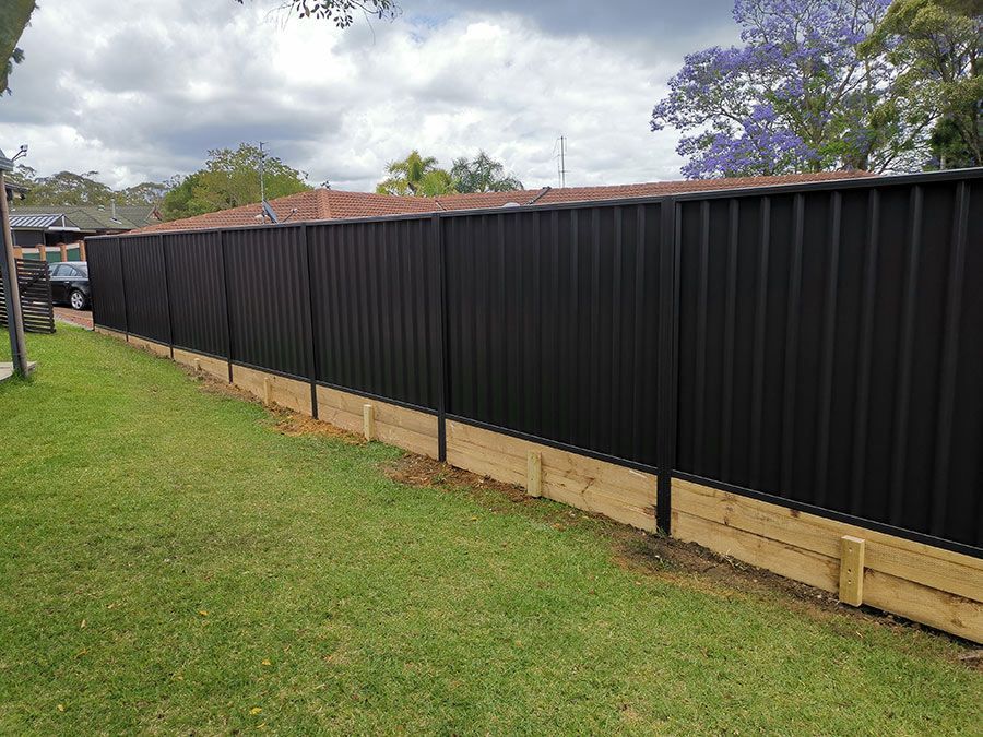 A Black Fence is Sitting on Top of a Lush Green Lawn — WeFence in Lisarow, NSW