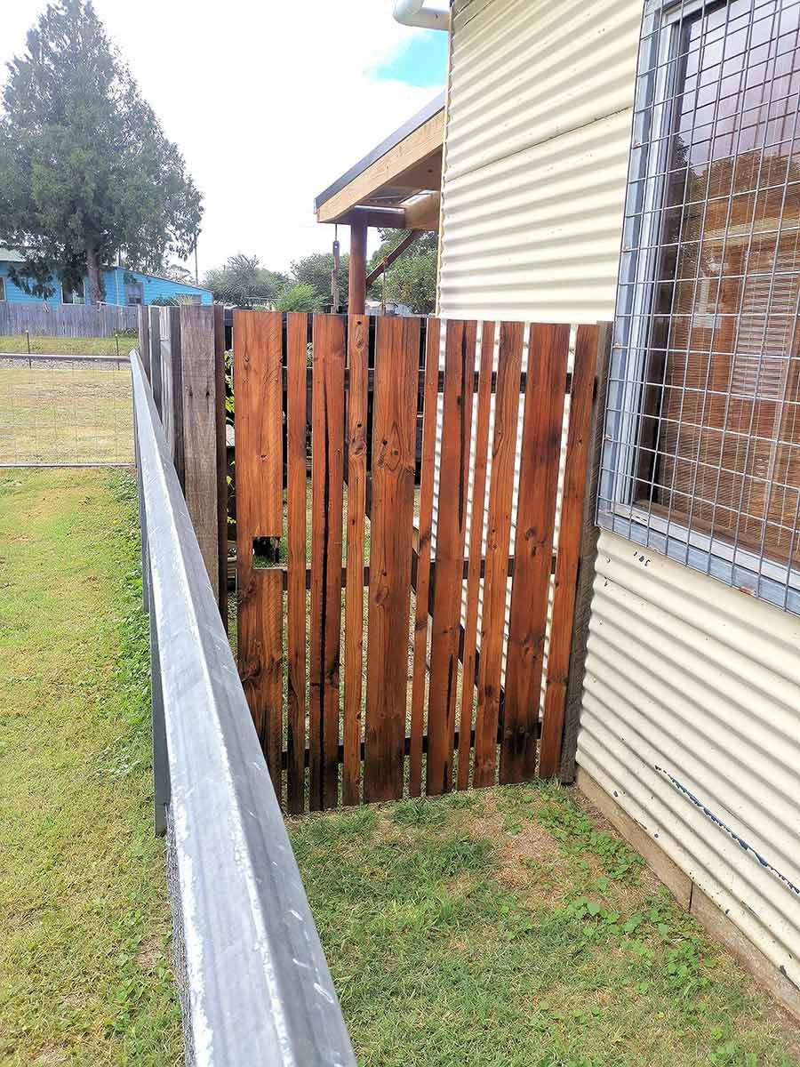 A Black Gate With a Stone Wall Behind It — WeFence in Lisarow, NSW