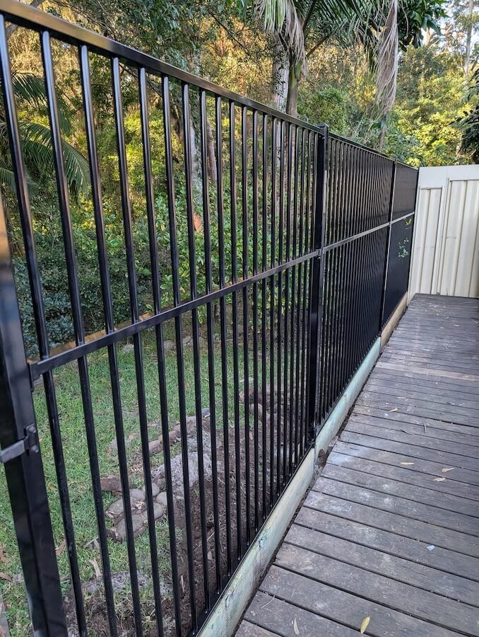 A Black Fence is Surrounding a Grassy Field Next to a House — WeFence in Lisarow, NSW