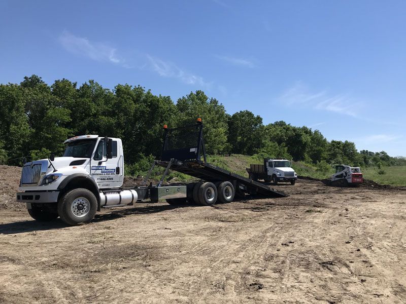 A truck with a flatbed trailer — Columbia, MO — Midway Hauling Containers & Roll-Offs