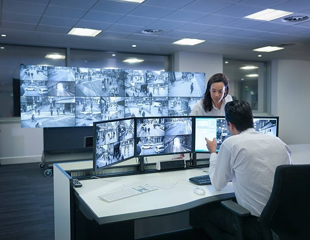 A security control room with multiple surveillance monitors showing live street camera feeds