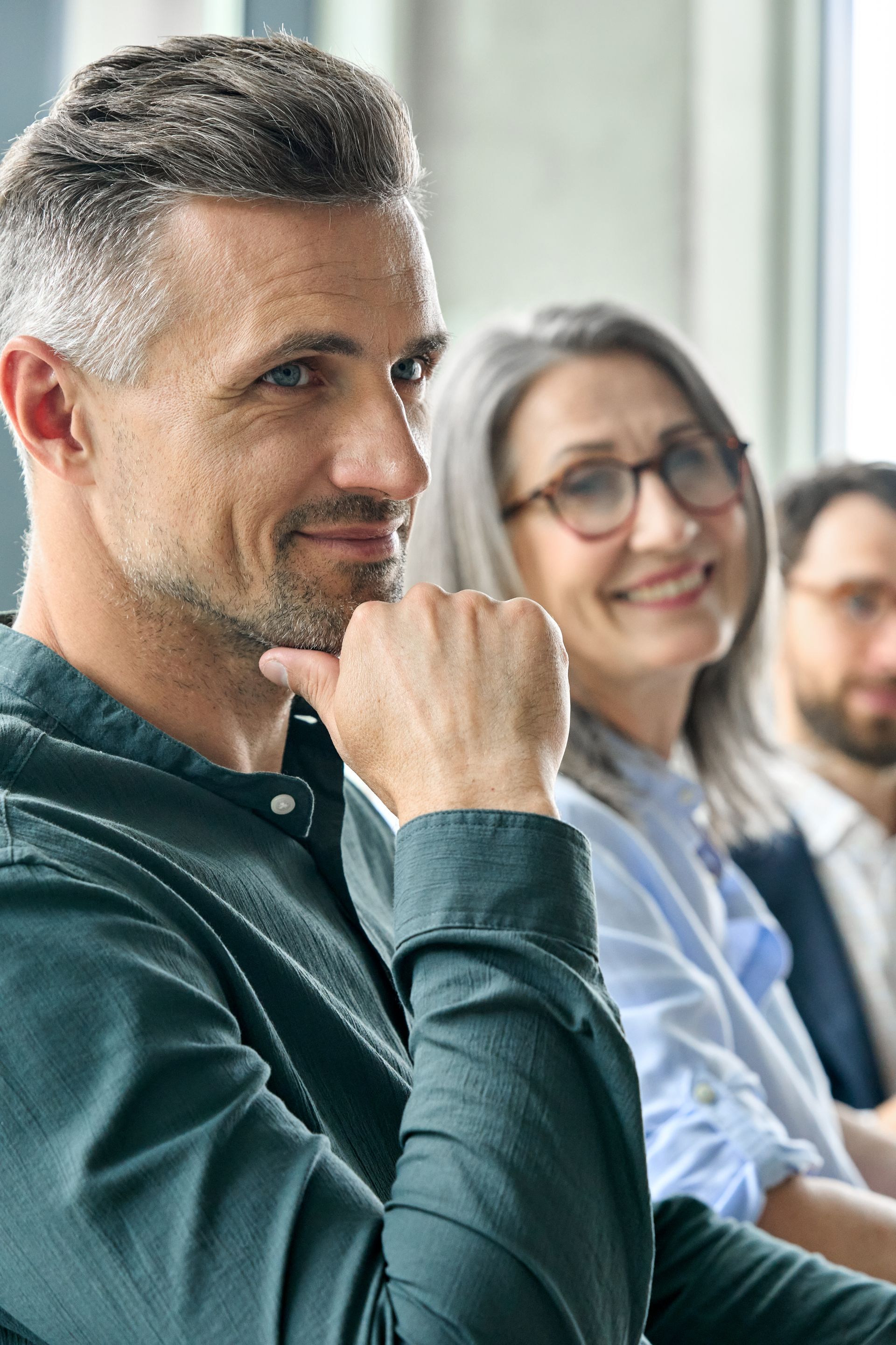 A man and a woman are sitting in a row with their hands on their chins.