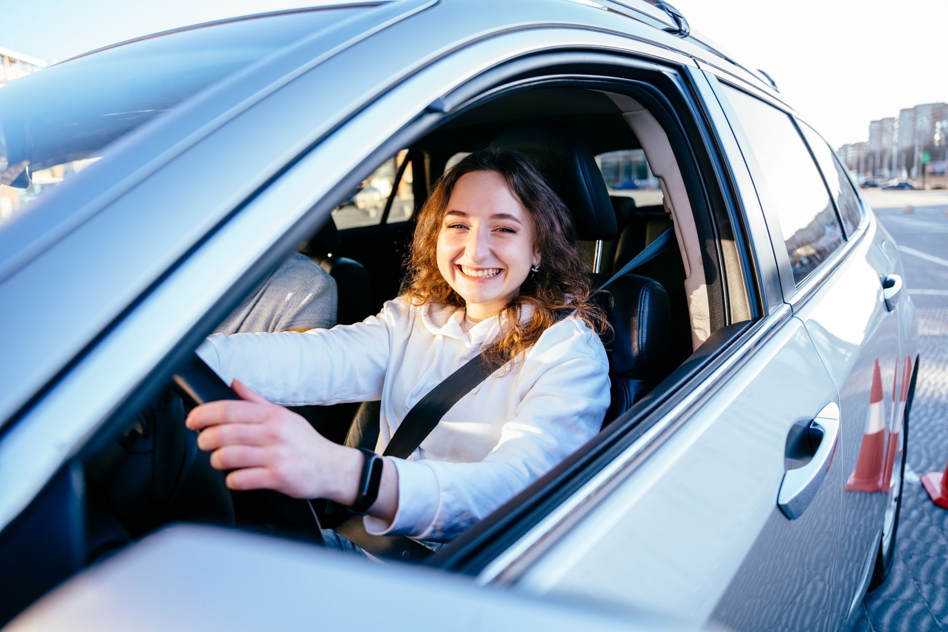 A woman is sitting in a car and smiling.