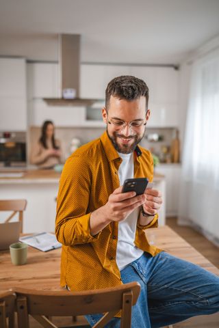 A man is sitting at a table looking at his cell phone.