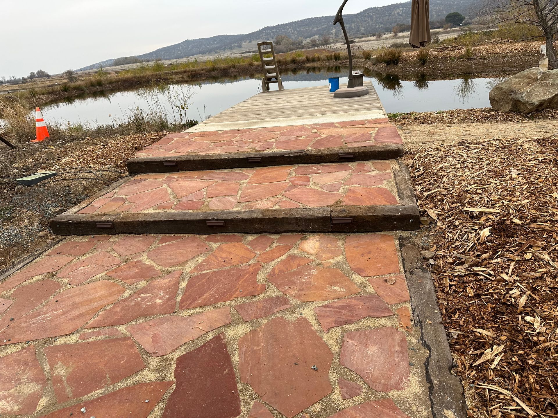 A stone walkway leading to a dock next to a pond.