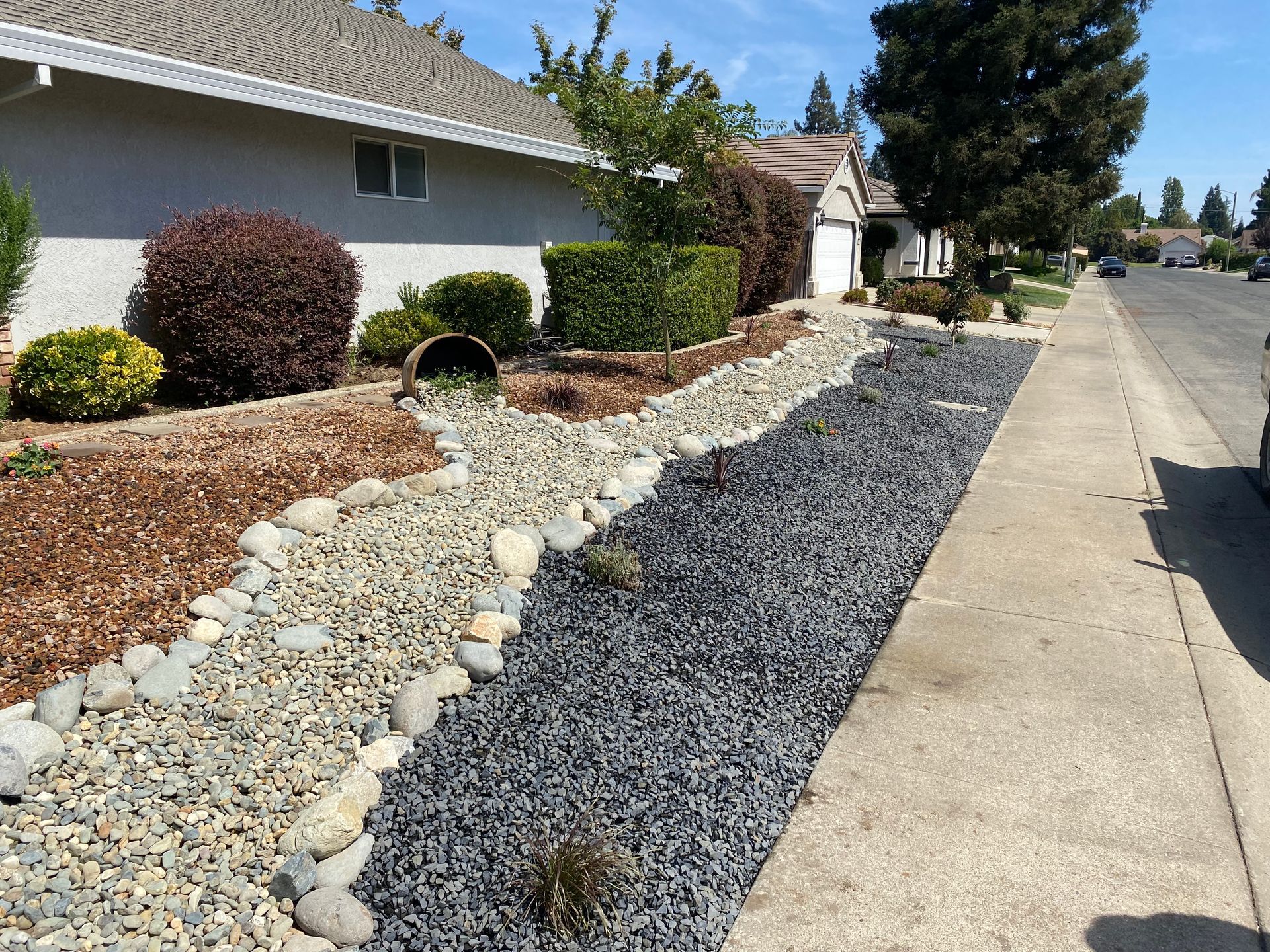 A sidewalk with rocks and mulch along the side of a house