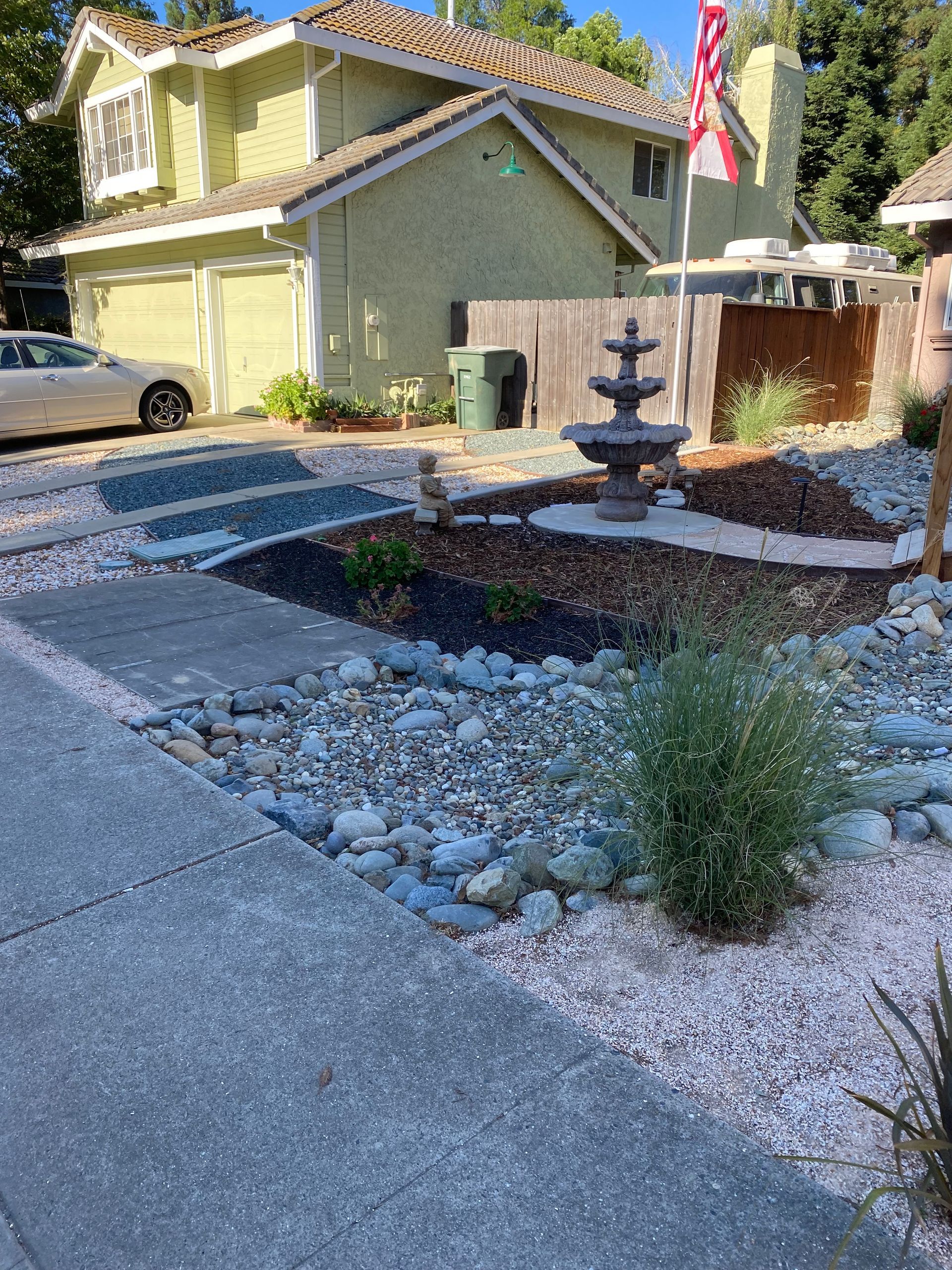 A house with a fountain in front of it and a car parked in front of it.