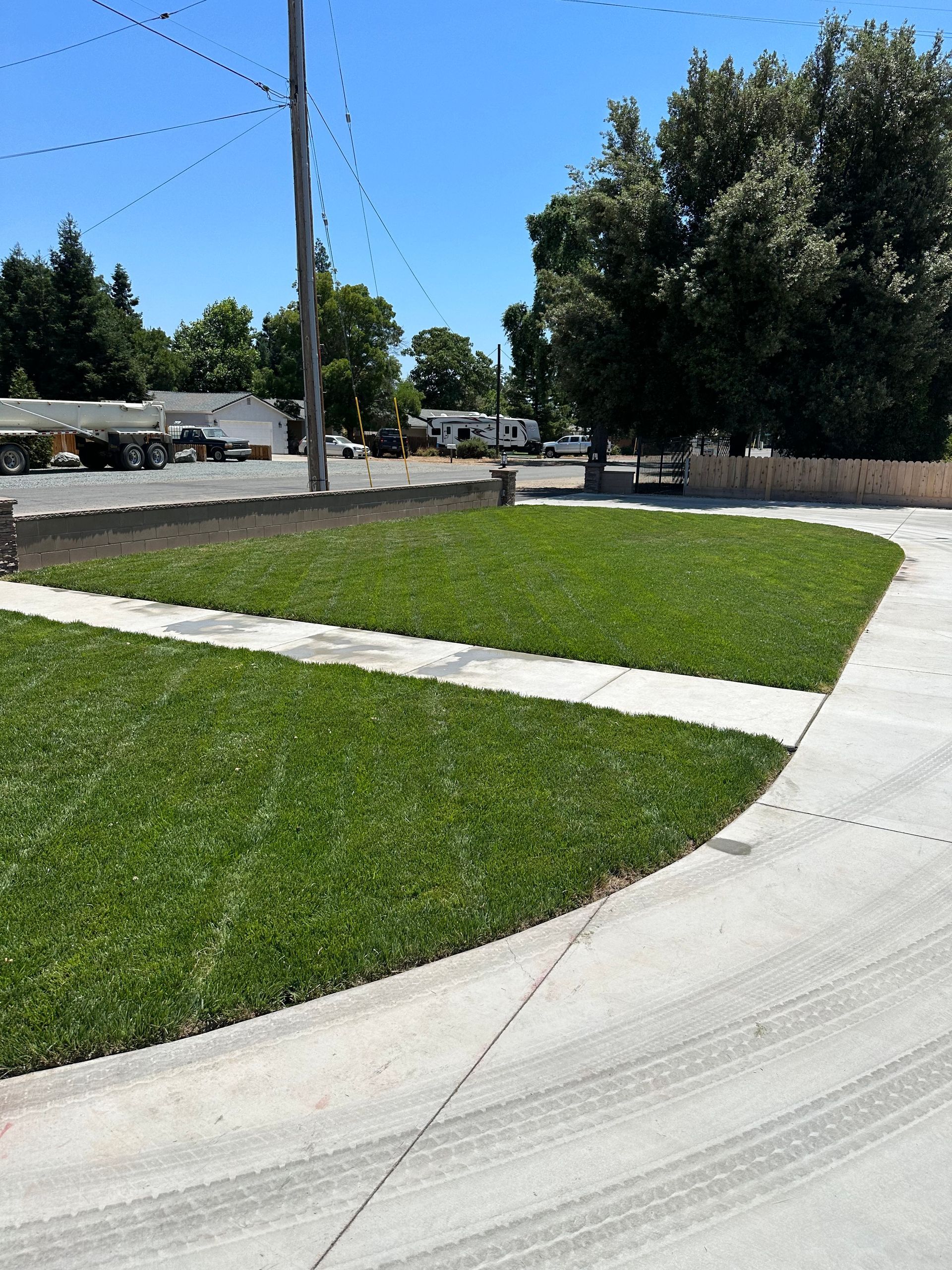 A concrete walkway going through a lush green field