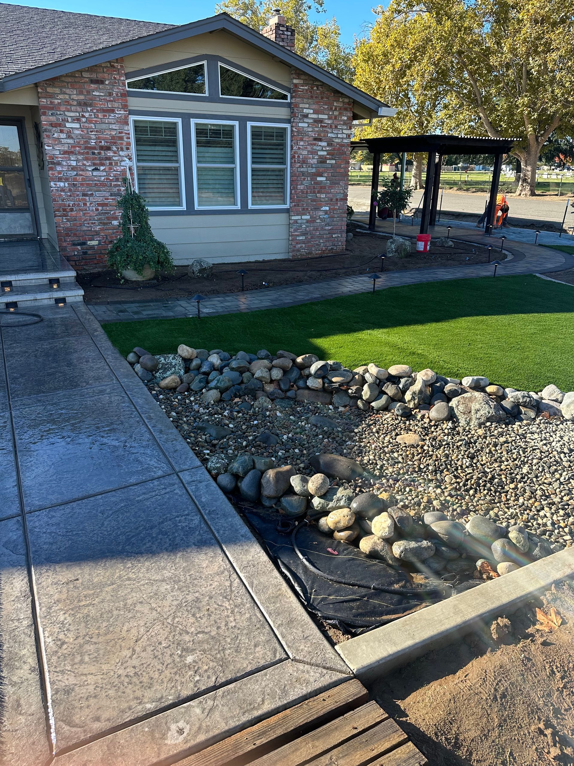 A brick house with a lush green lawn and rocks in front of it.