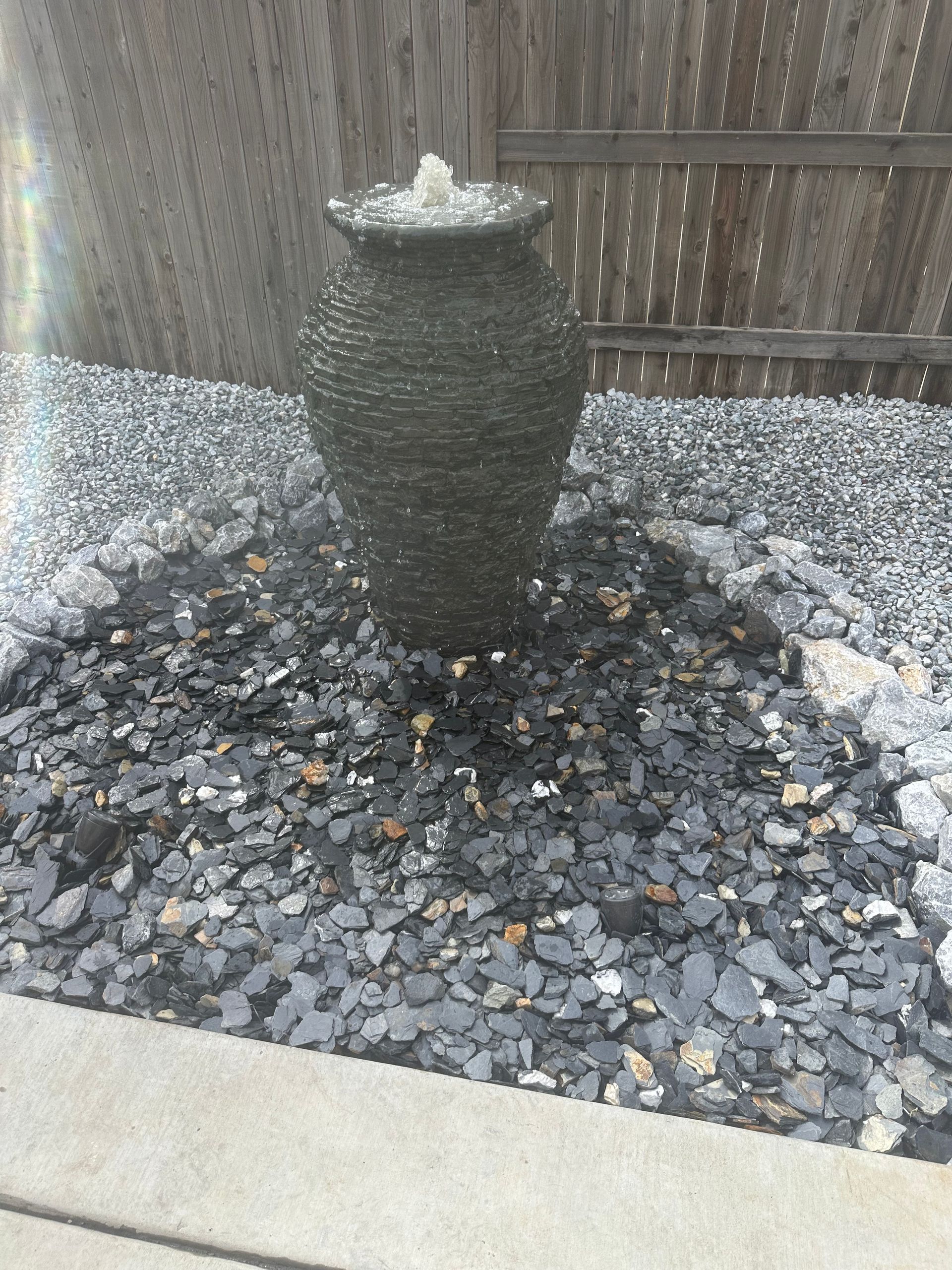 A fountain is sitting on top of a pile of gravel.